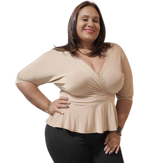 A woman posing in a beige, form-fitting, short-sleeved blouse with a round neckline, paired with black jeans.