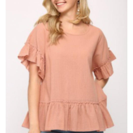 A female model wearing a beige tassel tie top with a round neckline and three-tier tassel detail, paired with blue jeans.