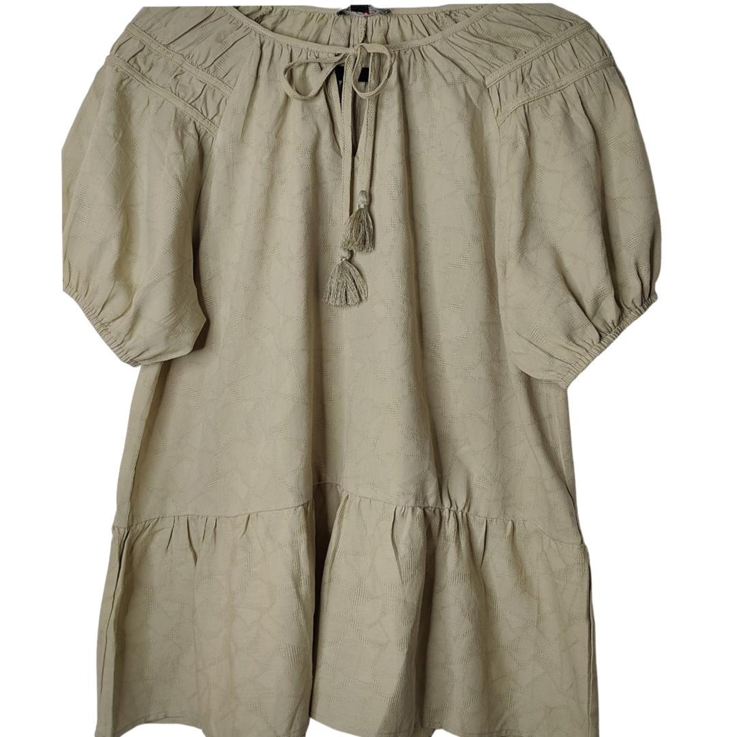 A beige jacquard woven blouse with a shirring detail and tassel tie.