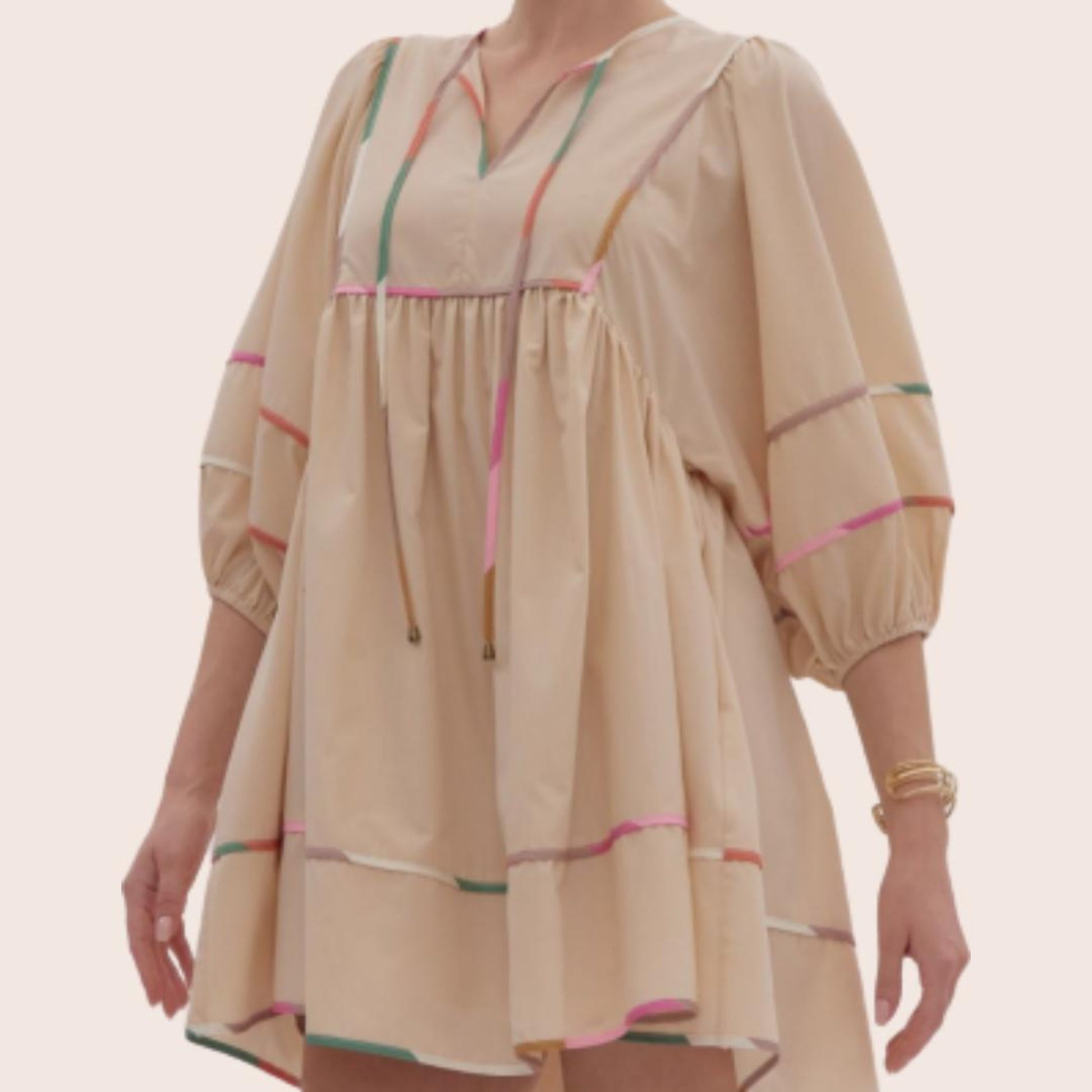 A bohemian-style dress in beige with colorful stripes, featuring three-quarter length puffed sleeves and a drawstring at the top.
