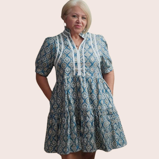 A woman wearing a v-neck, puff sleeve mini dress with a geometric pattern in blue and white colors.