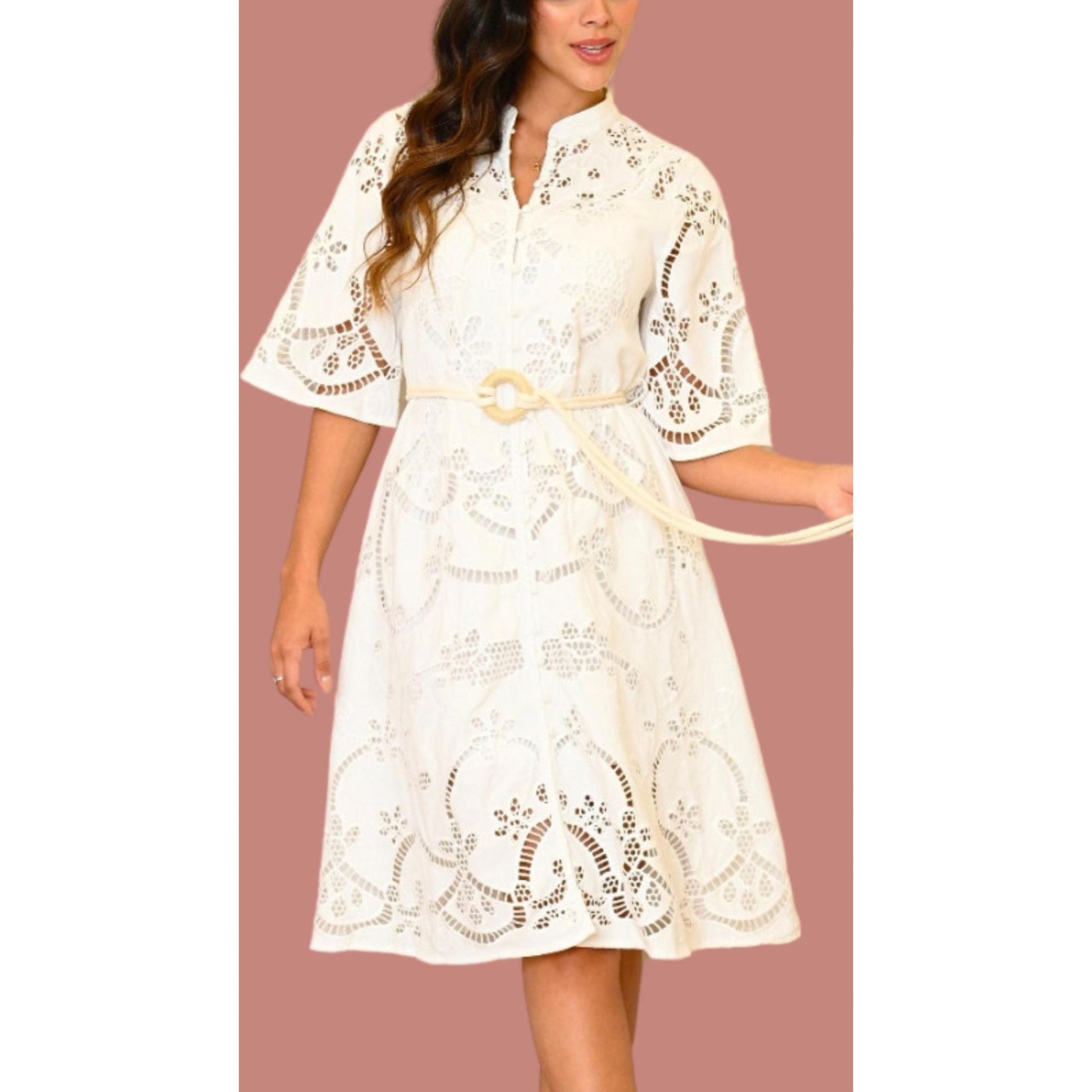 A woman wearing a white, floral print dress with long sleeves and a belt.