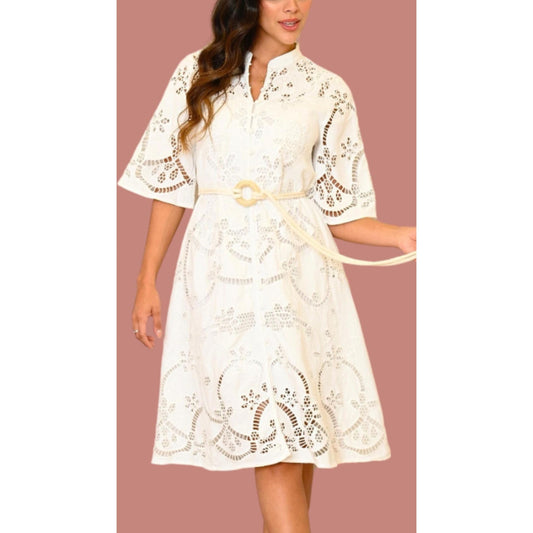 A woman wearing a white, floral print dress with long sleeves and a belt.