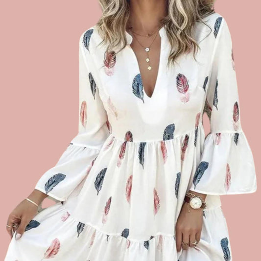 A woman wearing a white mini dress with a feather print, featuring a V-neckline and bell sleeves.