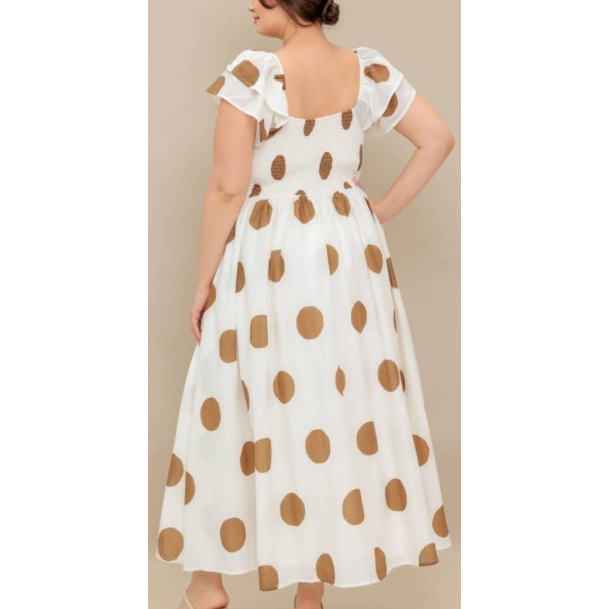 Woman wearing a white dress with brown polka dots against a beige background