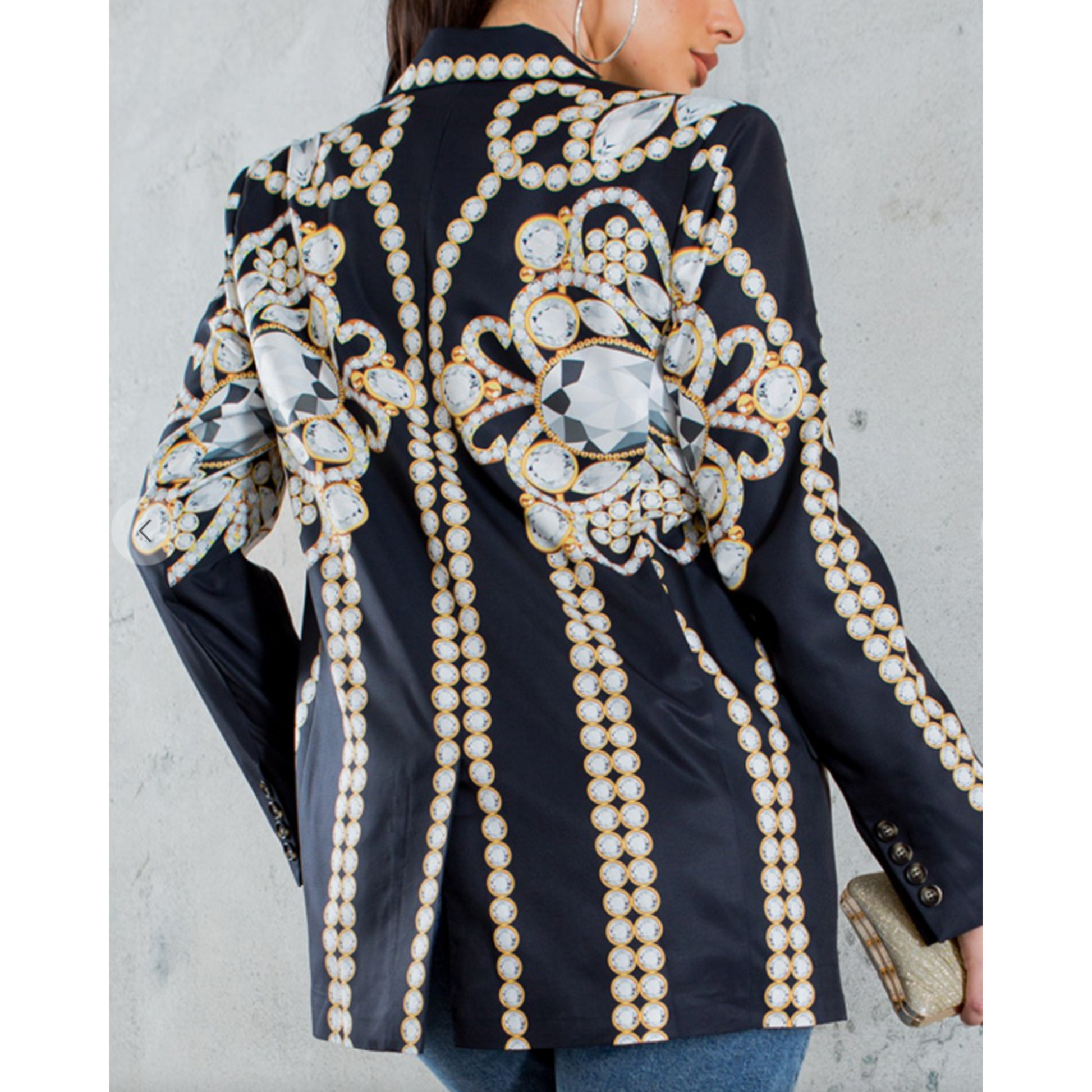 Black blazer with intricate pearl and gemstone embellishments on a plain background