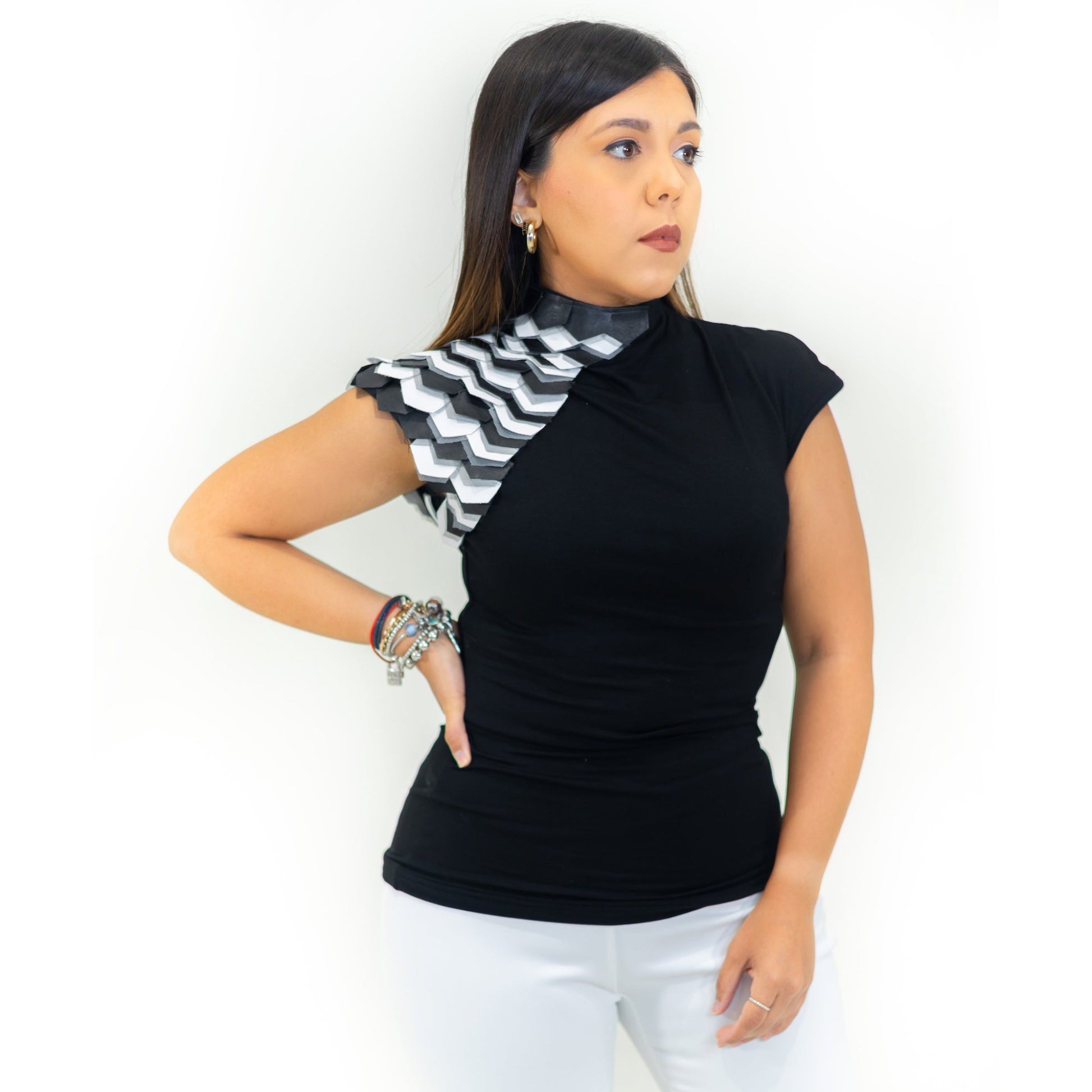 A model wearing a black short-sleeved blouse with leather details on the side and a high neck.