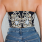 Person wearing a strapless top with intricate beadwork and blue jeans.