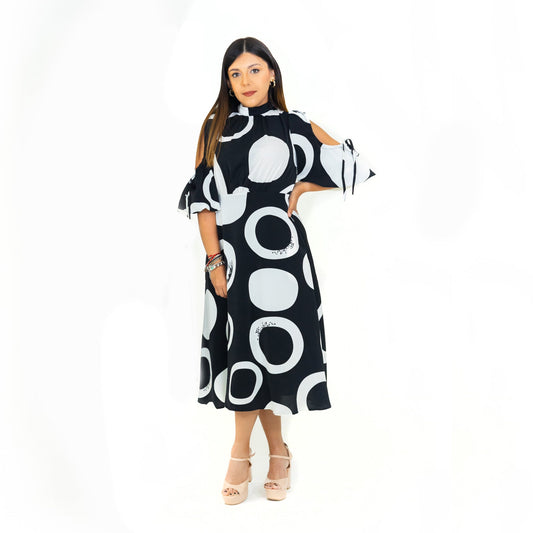 A model wearing a high collar black and white dress with a V-neckline and three-quarter sleeves, featuring a dotted pattern.